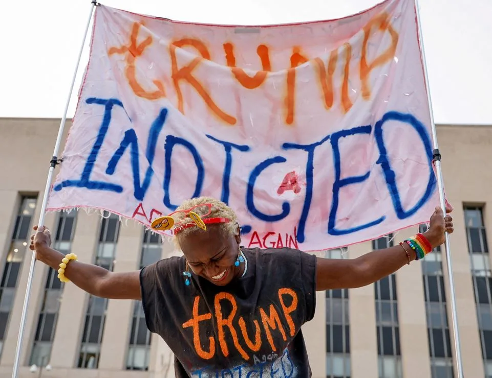 מפגינה נושאת שלט עם הכיתוב ''טראמפ נאשם'' מחוץ לביהמ''ש בוושינגטון